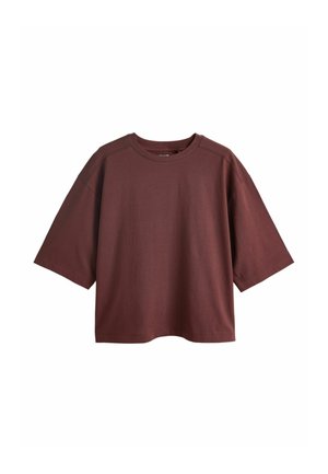 Bordo spalvos per dydį didesnis medvilninis marškinėlis trumpomis rankovėmis, apvaliu kaklu ir laisvo kirpimo. Glotni tekstūra, be matomų raštų ar spaudinių.