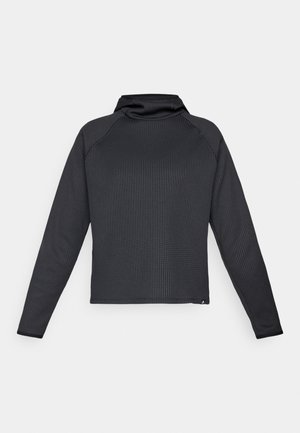 Dugi crni top s teksturiranim uzorkom, visokim ovratnikom i raglan rukavima. Rub je ravno odrezan, što ističe minimalistički dizajn.