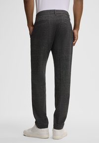 Pantaloni in felpa grigi con vestibilità dritta, dotati di due tasche posteriori, texture liscia e abbinati a sneaker bianche.