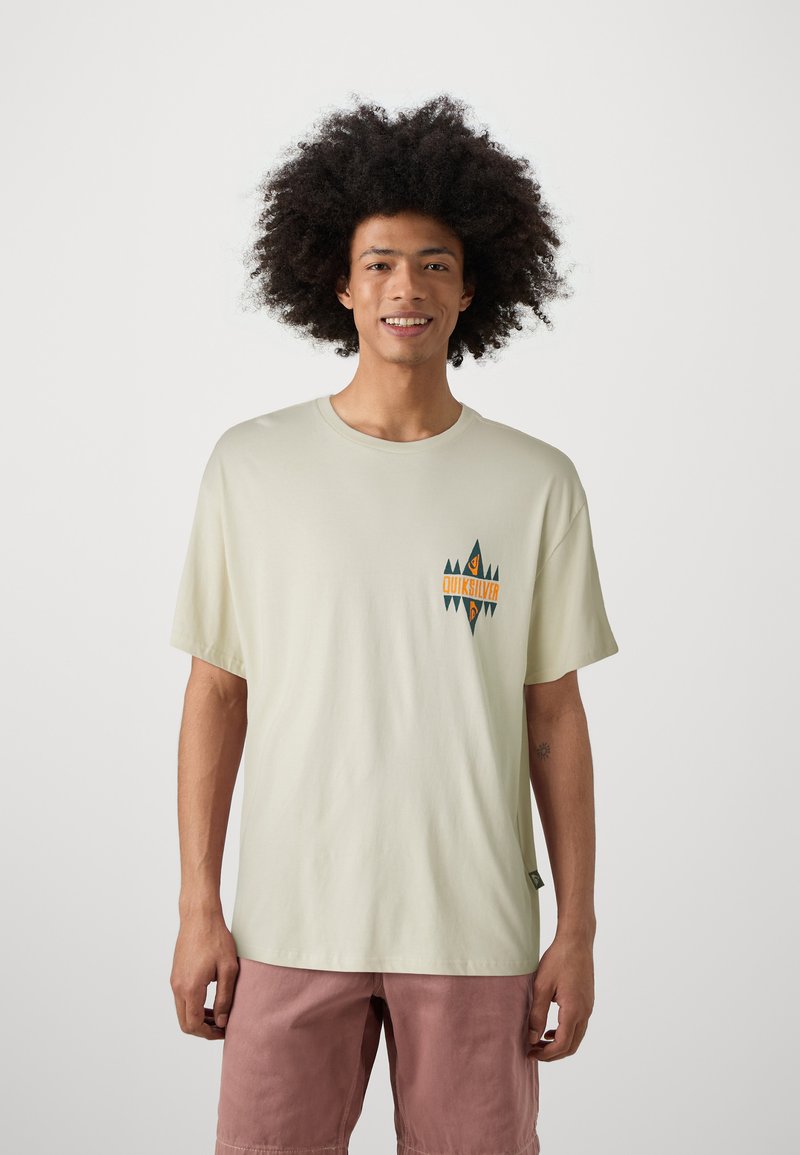 Lichtbeige t-shirt met korte mouwen, voorzien van een kleurrijk grafisch logo op de borst. De stof lijkt soepel en heeft een relaxed fit.