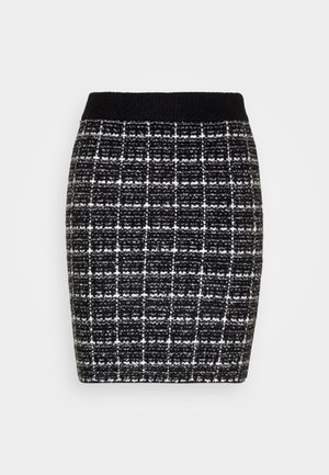 Jupe en crêpe à carreaux noir et blanc avec un tissu texturé, dotée d'une taille noire et d'une forme structurée.