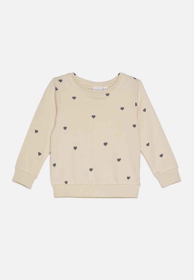 Sweatshirt beige clair avec motif de cœur gris, poignets et ourlet côtelés, encolure ronde et texture douce. Design décontracté adapté aux superpositions.