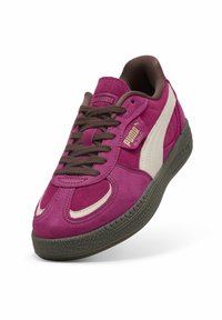 Sneakers Puma in suede fucsia audace con accenti crema, lacci marroni scuri e suola in gomma nera testurizzata. Presentano un'etichetta con il logo sul lato.