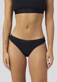 Bikini noir en coton avec une coupe taille basse et une ceinture élastique ornée d'un logo texturé. Texture lisse avec des coutures minimales et sans motifs.