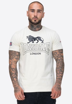 Weißes Baumwoll-T-Shirt mit kurzen Ärmeln, das eine schwarze Löwengrafik und den Text "Lonsdale London" zeigt. Enthält ein Union-Jack-Patch am Ärmel.