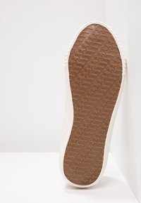 Hnědá gumová podešev boty s texturovaným vzorem, na kterém je logo značky "Pepe Jeans". Bílé, texturované boční okraje s hladkým povrchem.