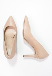 Chaussures à talons aiguilles beiges avec un bout pointu, une texture en cuir lisse et un talon stiletto élancé. Pas de motifs ni d'accents visibles.