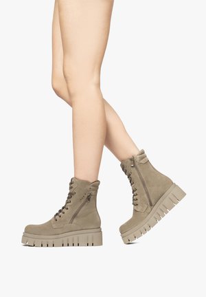 Stivali in suede color taupe con suola in gomma spessa, lacci sulla parte anteriore e dettaglio con zip laterale. Dotati di una caviglia imbottita per il comfort.