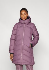 Lila puffjacka med huva, med ett chevronmönster, dragkedjestängning och sidofickor. Tillverkad av lätt, isolerande material.