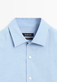Světle modrá polokošile s texturovanou tkaninou, knoflíkovými zapínáními a štítkem s názvem značky Massimo Dutti.