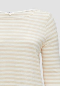 Lange mouwen shirt in lichtbeige met witte horizontale strepen. Zacht materiaal, ronde halslijn, gestikte details en een losse pasvorm.
