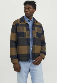 Ruskea ja laivansiniset ruudullinen takki nappikiinnityksellä, rintataskuilla ja kauluksella, kerroksittain denimitakin päällä.