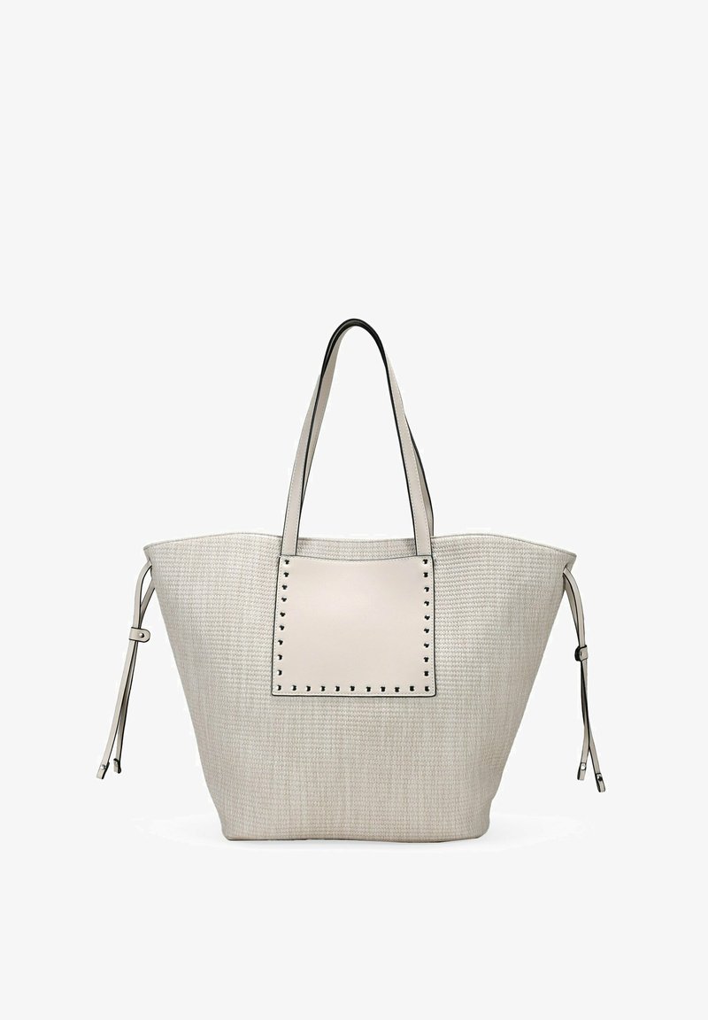 Bolso tote de ratán beige con un panel de cuero liso en contraste y acentos de tachuelas. Presenta dos asas resistentes y lazos laterales ajustables.
