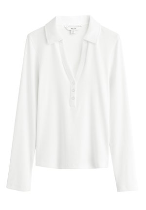 Polo bianca a maniche lunghe a coste con colletto e tre bottoni sulla patta, mostrata distesa su sfondo bianco.