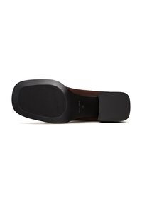 Talpă din suede maro cu un design lat și plat. Talpă exterioară din cauciuc negru texturat cu un pattern nervurat și margini rotunjite.