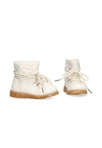 Botas de tobillo blancas con textura acolchada y cordones beige. Suela de goma en un tono transparente. Diseño de caña alta con un detalle de cremallera lateral.