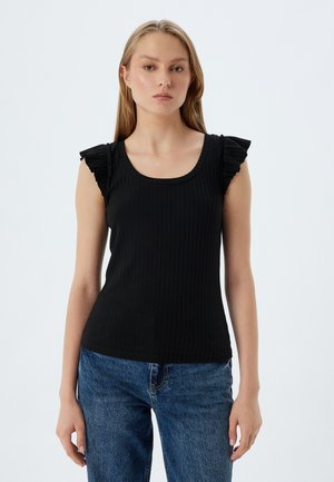 Top negro de canalé con escote redondo y detalles de volantes en los hombros. Combinado con jeans de mezclilla azul claro.