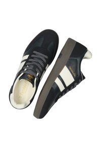 Czarno-białe trampki z cholewką wykonaną z skóry i zamszu, charakteryzujące się niskim profilem, szarymi sznurówkami oraz teksturowaną brązową gumową podeszwą.