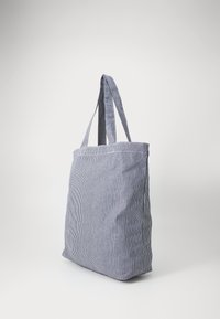 Torebka na ramię w paski w kolorze granatowym i białym, wykonana z lekkiego materiału. Posiada dwa solidne uchwyty oraz pojemny, nieukierunkowany design.