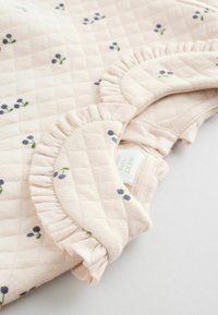 Tessuto trapuntato rosa chiaro con stampa floreale; presenta un colletto arricciato e chiusura a bottoni; texture morbida con piccoli motivi navy e verdi.