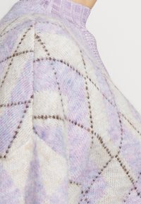 Strickpullover mit einem Rautenmuster in pastelllila und beige, kontrastierendem braunem Nähten und einem hohen Rippkragen.