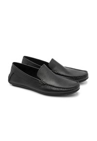 Mocasines de cuero negro con acabado texturizado, diseño sin cordones, punta redondeada y detalles de costura sutiles a lo largo de los bordes.