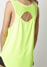 Top atlético sin mangas de color verde neón con un detalle de corte redondo en la parte posterior y fabricado en una tela ligera y transpirable.