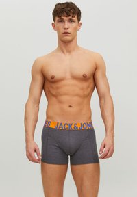 Graue Boxershorts mit einem orangen "JACK & JONES" Logo-Bund, aus einem glatten, elastischen Material gefertigt, mit passendem Design und mittelhohem Schnitt.
