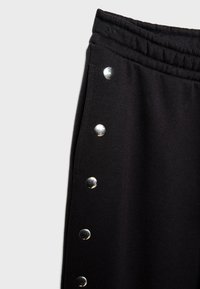 Schwarze Jogginghosen aus glattem Stoff mit elastischem Bund und silbernen Druckknöpfen an der Seite für eine verstellbare Passform.