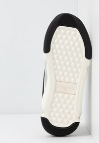 Suela de zapatilla en blanco y negro con amortiguación texturizada, presenta un borde superior liso, suela de goma y un logo grabado "Blauer USA".