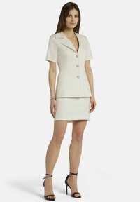 Witte op maat gemaakte blazer met korte mouwen, v-hals en drie knopen, gecombineerd met een nauwsluitende mini-rok. Glad stof, minimalistisch ontwerp.