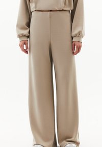 Pantalones de pierna ancha beige hechos de una tela suave, con una cintura alta y una textura lisa. Diseño simple sin patrones ni acentos visibles.