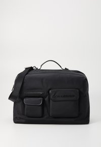 Sac en nylon noir avec deux poches avant, bandoulière réglable et poignée supérieure. Dispose d'une fermeture éclair et d'un détail de marque en relief.
