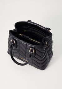 Fekete steppelt bőr kézi táska arany színű fémalkatrészekkel. Két robusztus fogantyúval és belső zsebekkel rendelkezik, melyek struktúrált formát biztosítanak.