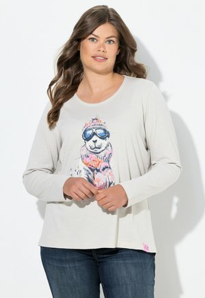 Maglietta a maniche lunghe color beige chiaro con una grafica di un orso con occhiali da sole, con accenti colorati, scollo rotondo e vestibilità ampia.