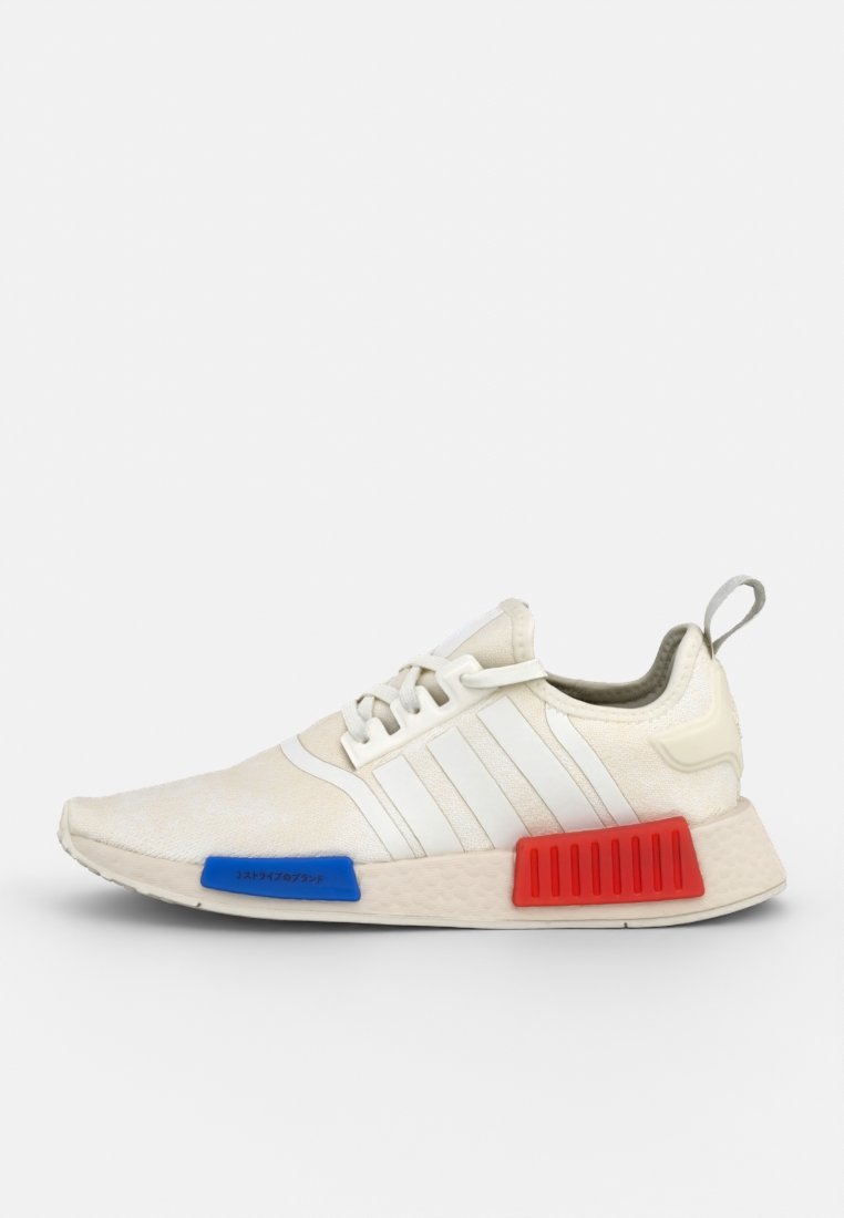 Weißer Sportschuh mit drei weißen Streifen, blauen und roten Akzenten an der Sohle, strukturiertem Material und Schnürdesign.