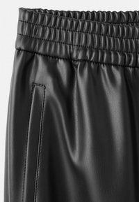 Crne trenerske hlače od kože s teksturiranim završetkom, s elastičnim pojasom i bočnim džepom za dodatnu praktičnost.