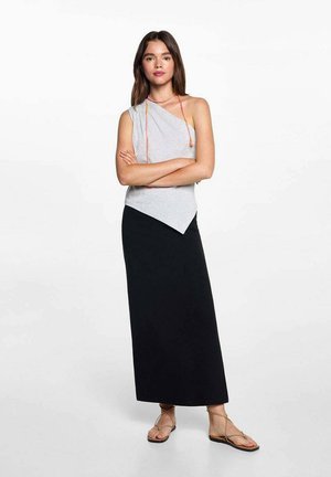 Graues One-Shoulder-Top, schwarze knöchellange Rock und helle Sandalen mit dünnen Riemen. Glattes Material, einfaches Design und kontrastierendes Farbschema.