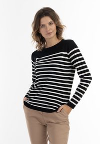 Pulover cu dungi alb-negru, cu mânecă lungă și gât rotund, asortat cu pantaloni bej. Textură netedă, croială casual.