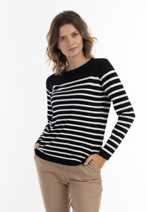 Valko-musta raidallinen pullover neule pitkillä hihoilla ja pyöreällä kaula-aukolla, yhdistettynä beigepantoihin housuihin. Silkkinen pinta, rento istuvuus.