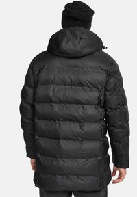 Chaqueta de plumas negra con capucha ajustable, costuras diagonales, forma alargada y tejido texturizado. Cuenta con cremallera frontal y bolsillos laterales.