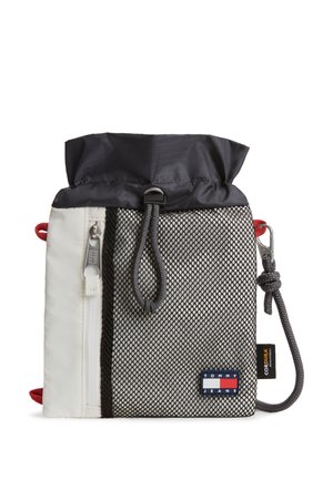Klein trekkoordzakje met zwarte bovenzijde, wit zijpaneel met rits, grijs gaas aan de voorkant en een Tommy Jeans-logo patch rechtsonder.