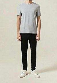 Grå kortärmad t-shirt kombinerad med svarta slim fit-byxor och vita sneakers. Tyget verkar mjukt och har en enkel, minimalistisk design.