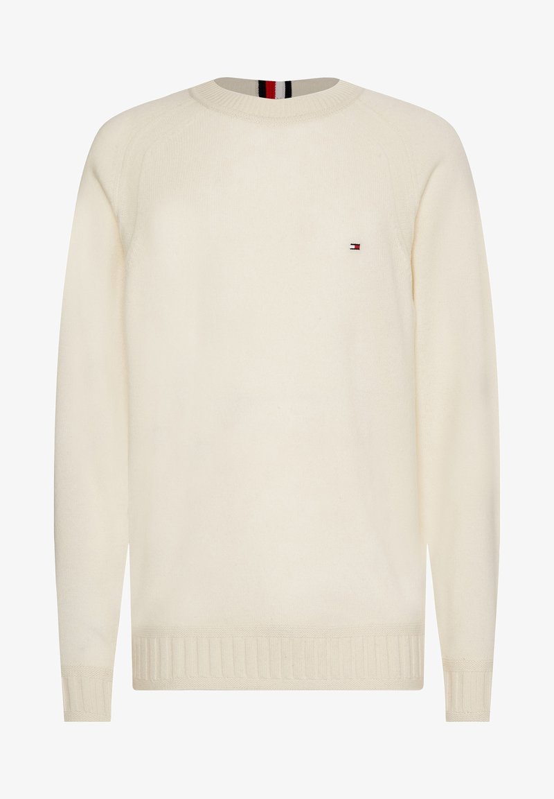 Pull à manches longues couleur crème avec col rond, poignets et bas côtelés, orné d'un petit logo rouge, blanc et bleu sur la poitrine gauche.