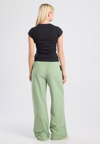 Black fitted short-sleeve top paired with lightweight, green gingham check wide-leg pants featuring an elastic waistband.