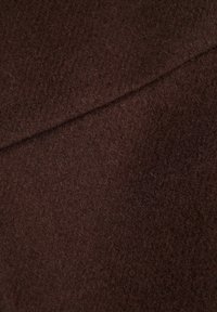Tela de fieltro marrón con una superficie suave y texturada. Presenta un color uniforme, mostrando ligeras variaciones en el tono y pequeñas fibras.