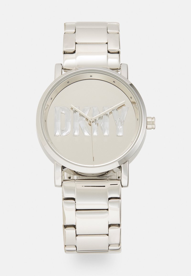 Silver metal watch with an oval face. Face features bold "DKNY" lettering. Bracelet has a polished finish with rounded links. Simple hour markers.