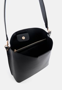 Bolso de mano de cuero negro con cierre de imán en tono dorado y un compartimento con cremallera, con un diseño liso y estructurado.