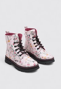 Botas rosas con cordones, con estampado floral, suelas negras y forro magenta, mostradas una al lado de la otra sobre un fondo liso.