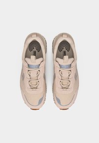 Ζευγάρι ανοιχτό μπεζ αθλητικά παπούτσια από δίχτυ και σουέντ με κορδόνια και επωνυμασμένες εσωτερικές σόλες, εμφανιζόμενα από επάνω σε λευκό φόντο.